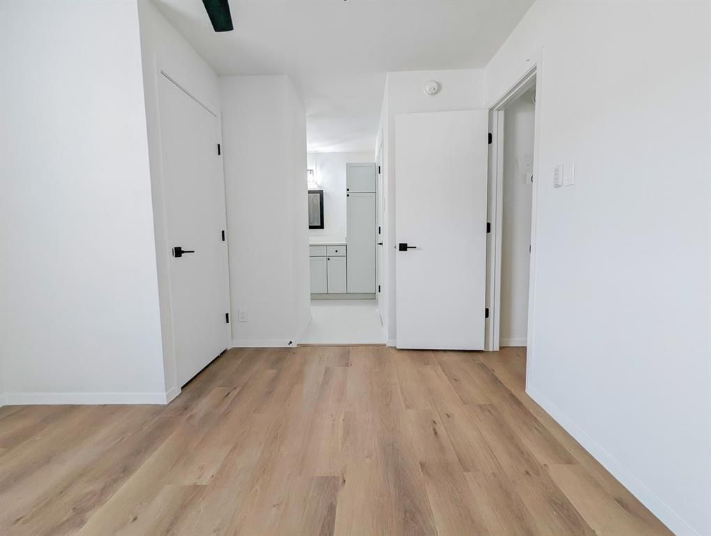 An empty bedroom with hardwood floors and white walls.