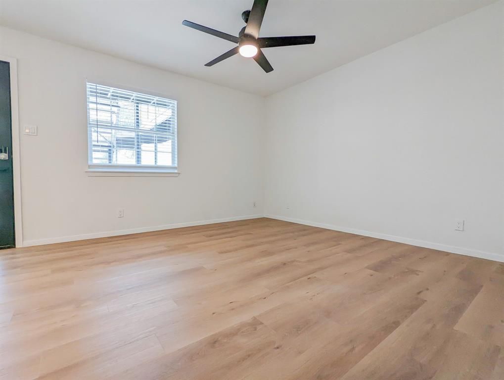An empty room with hardwood floors and a ceiling fan