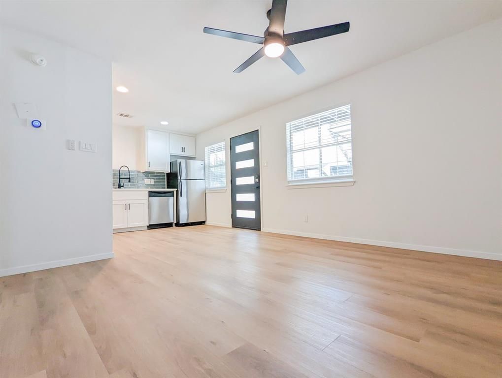 An empty living room with hardwood floors and a ceiling fan.