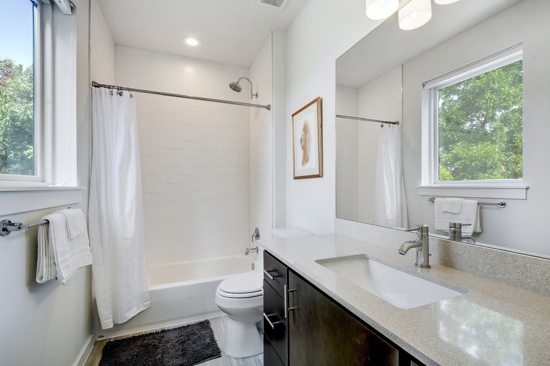 A bathroom with a toilet , sink , shower and window.
