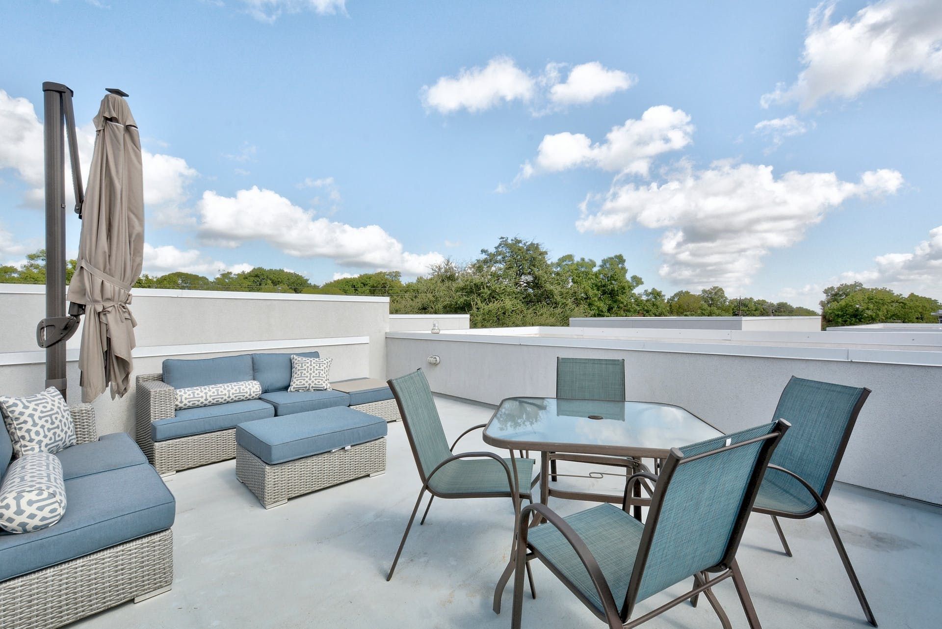 A patio with a table , chairs , a couch and an umbrella.