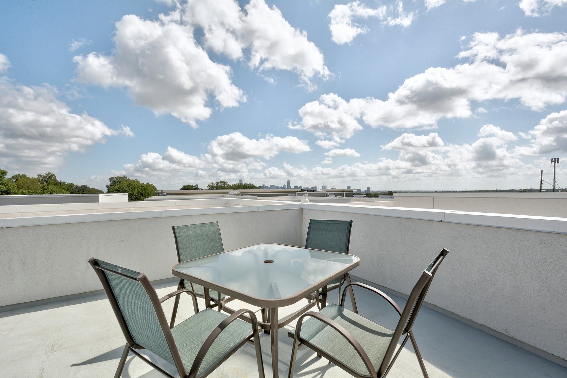 A table and chairs on a balcony with a view of a cloudy sky