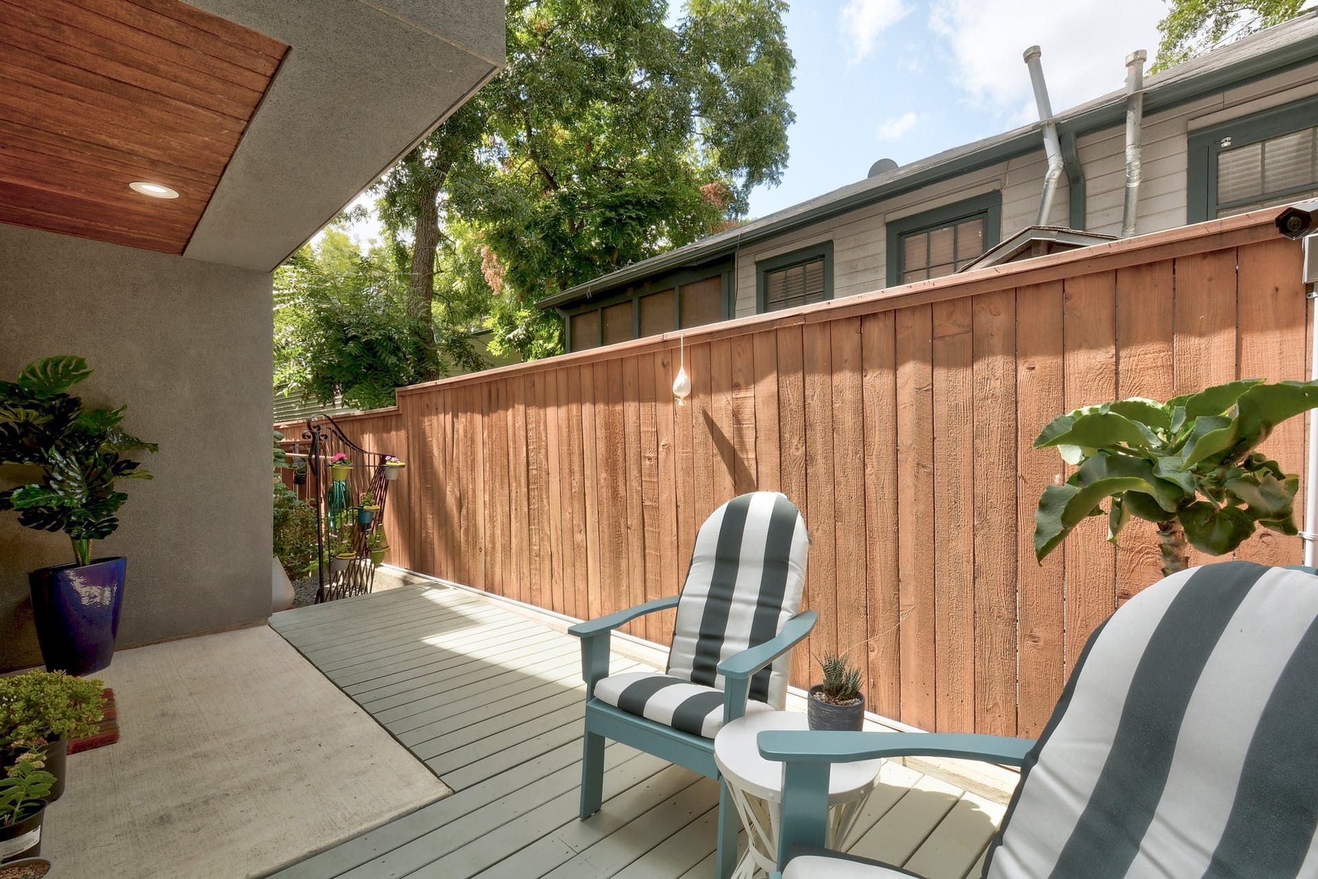 A patio with a wooden fence and two chairs