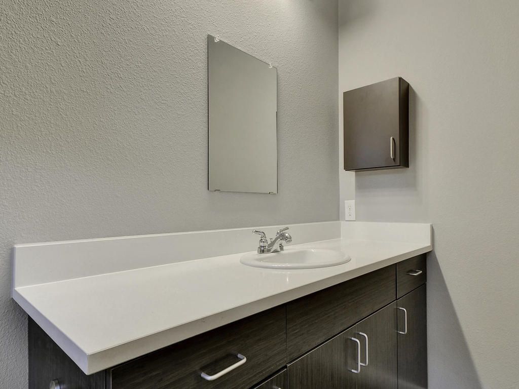 A bathroom with a sink , mirror and cabinets.