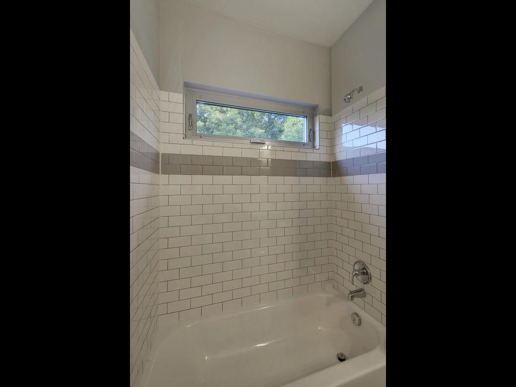 A bathroom with a tub and a shower with a window.