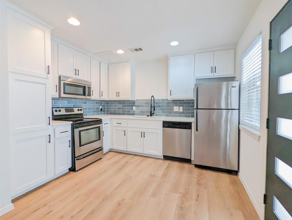 A kitchen with stainless steel appliances and white cabinets.