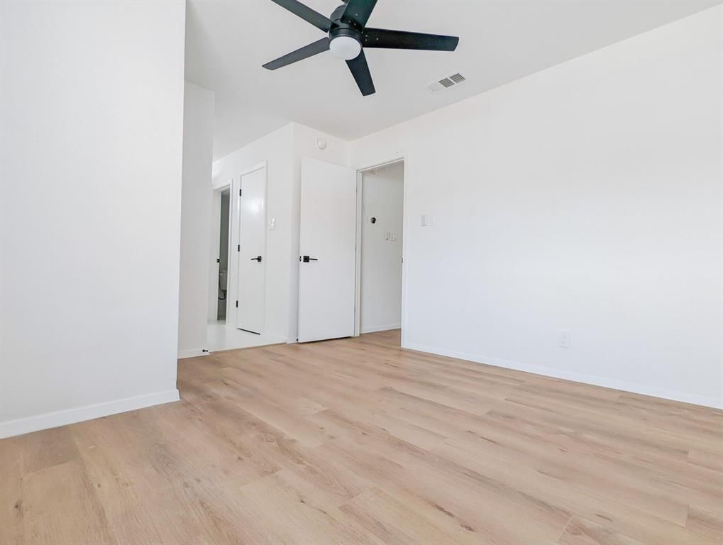 An empty bedroom with hardwood floors and a ceiling fan.