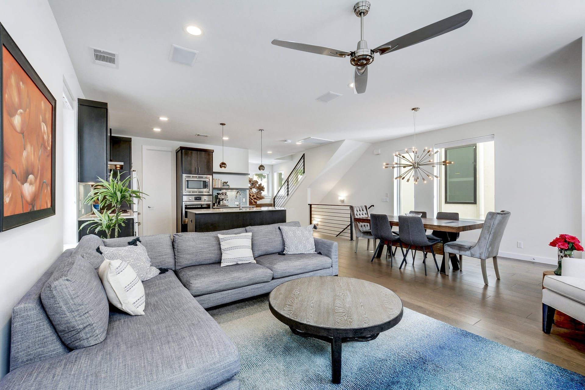 A living room with a couch , table , chairs and a ceiling fan.