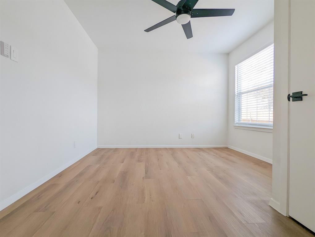 An empty bedroom with hardwood floors and a ceiling fan.