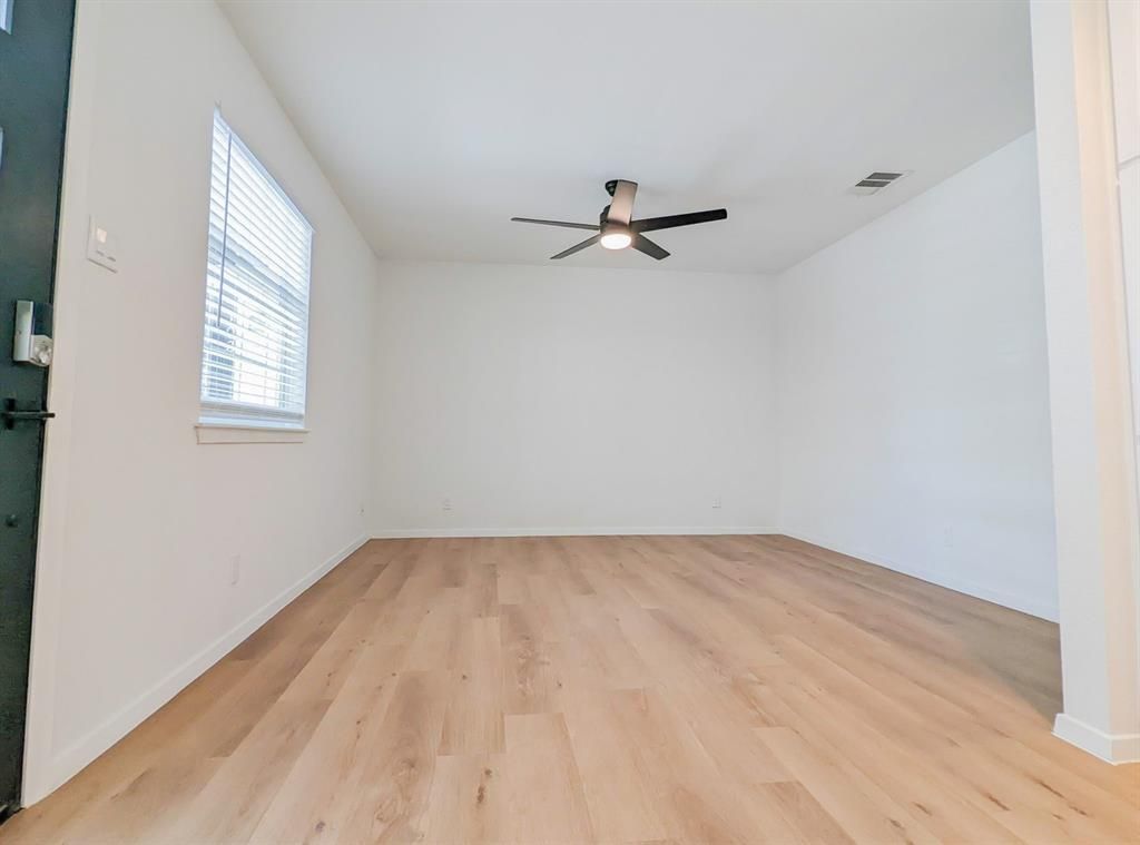 An empty living room with hardwood floors and a ceiling fan