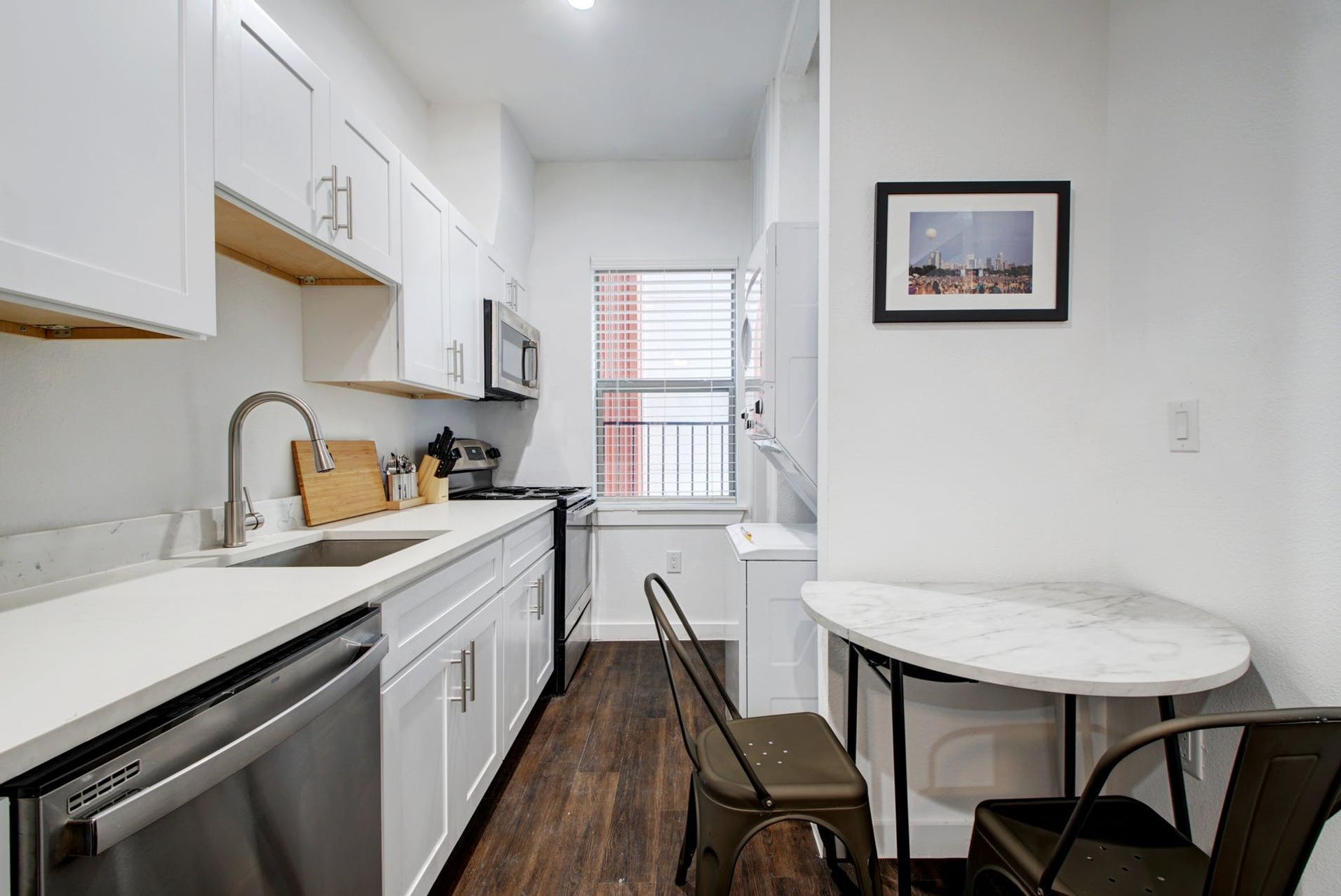 A kitchen with white cabinets , stainless steel appliances , a table and chairs.