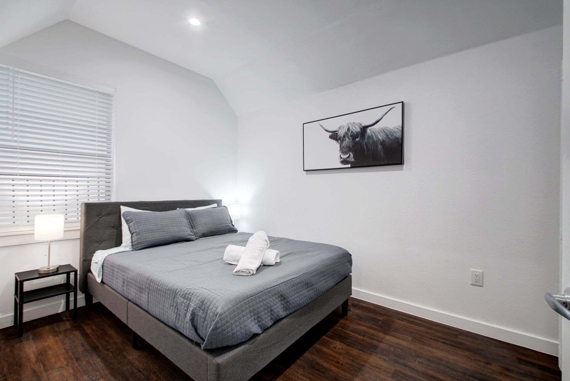 A bedroom with a king size bed and a picture of a bull on the wall.