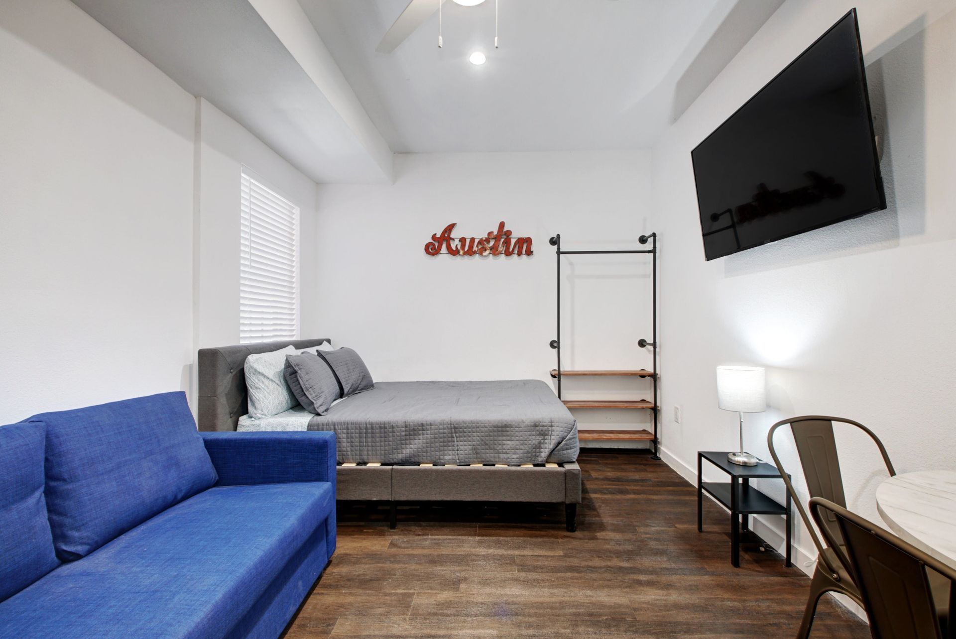 A bedroom with a blue couch a bed and a flat screen tv