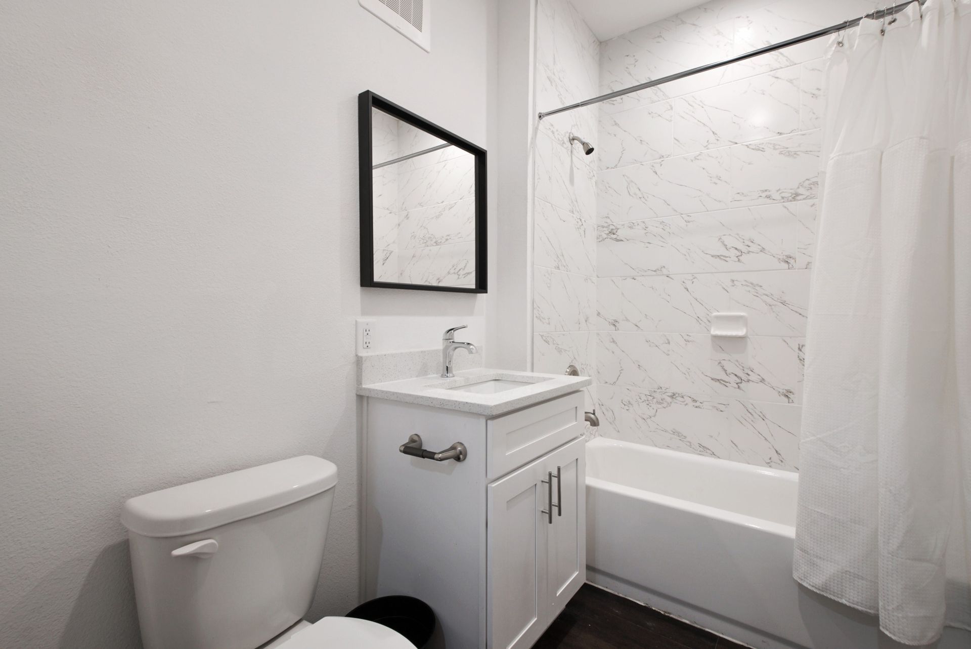 A bathroom with a toilet , sink , mirror and bathtub.