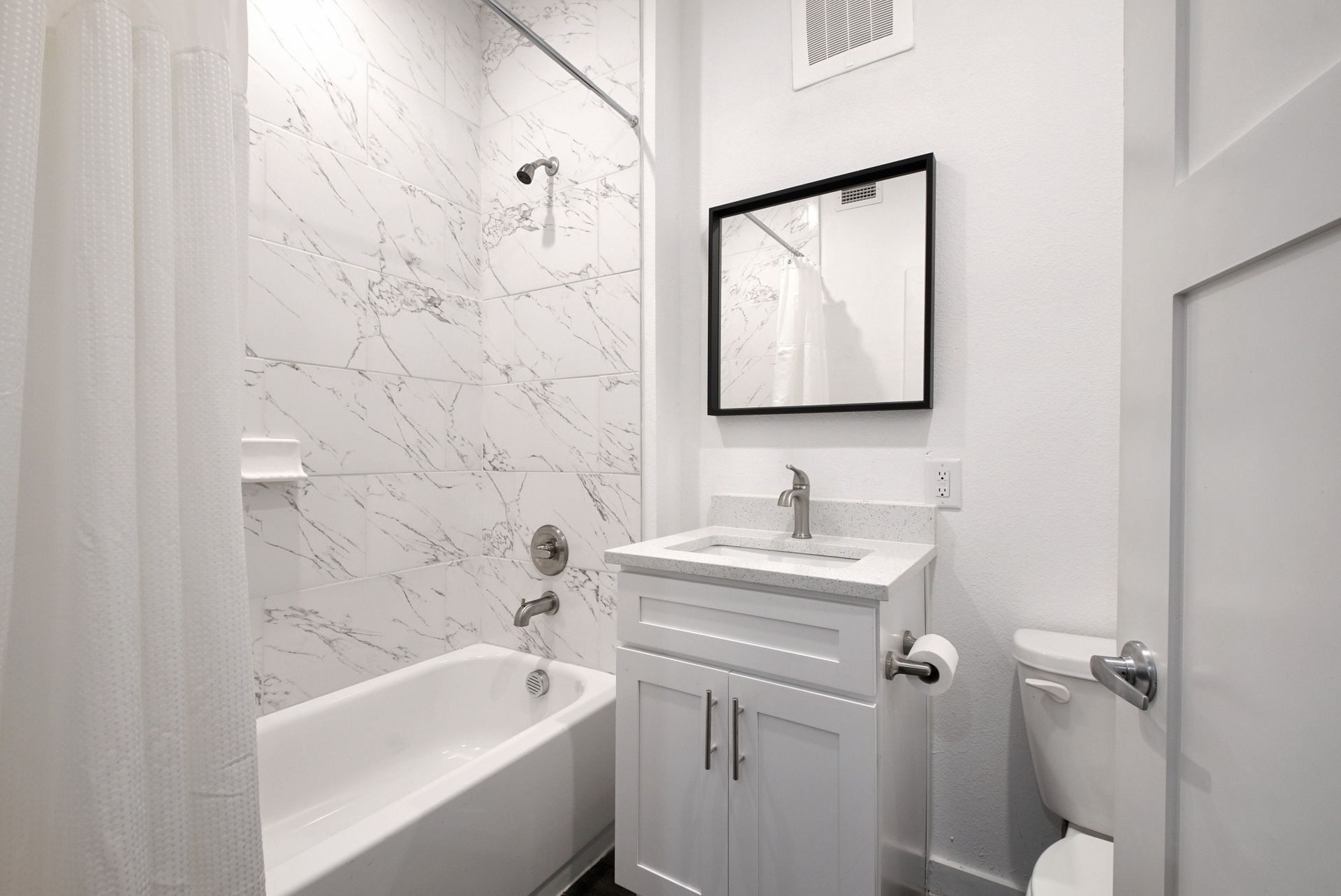 A bathroom with a tub , sink , toilet and mirror.