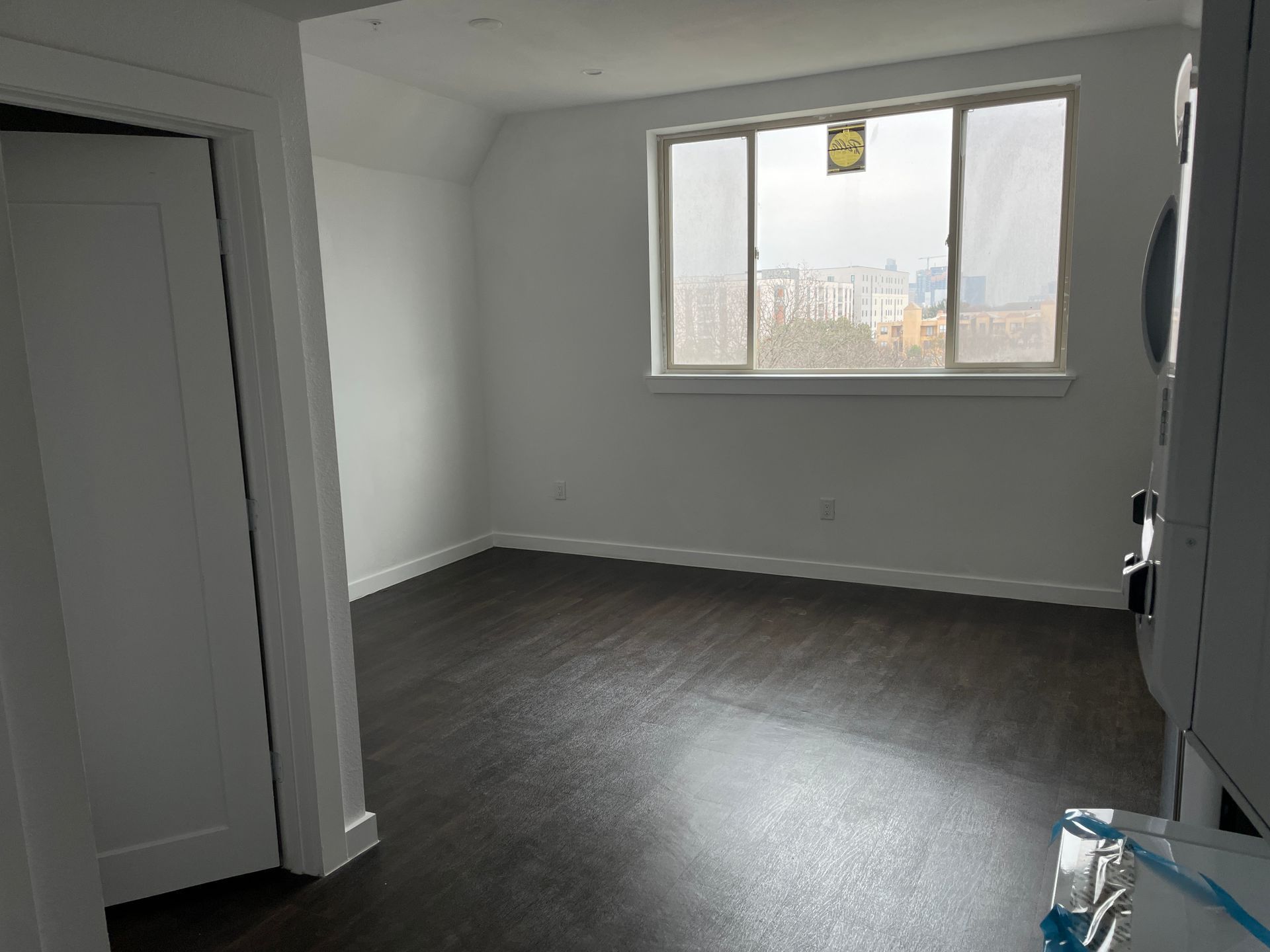 An empty room with hardwood floors and a large window.