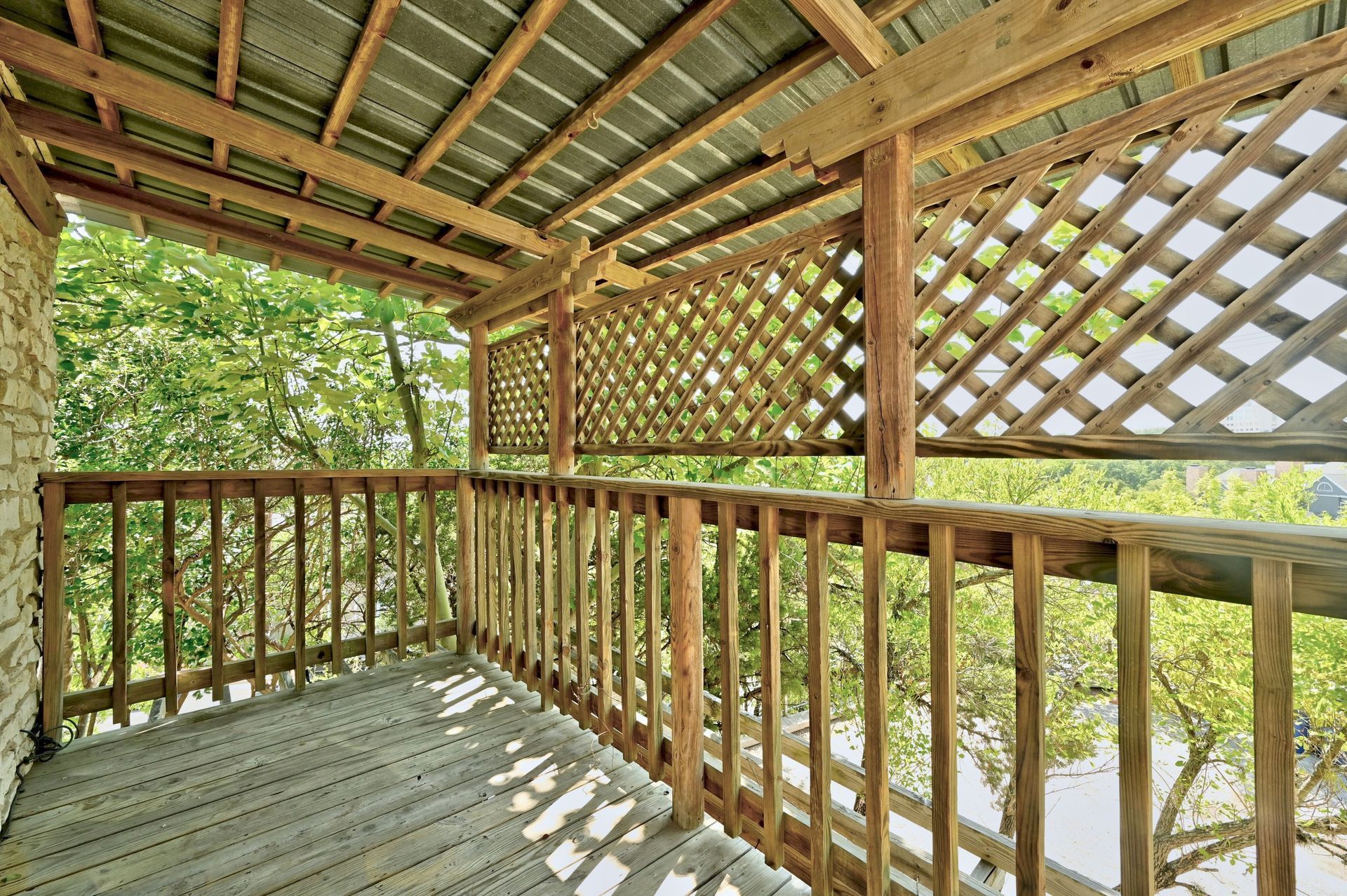 A wooden deck with a lattice fence and a metal roof.