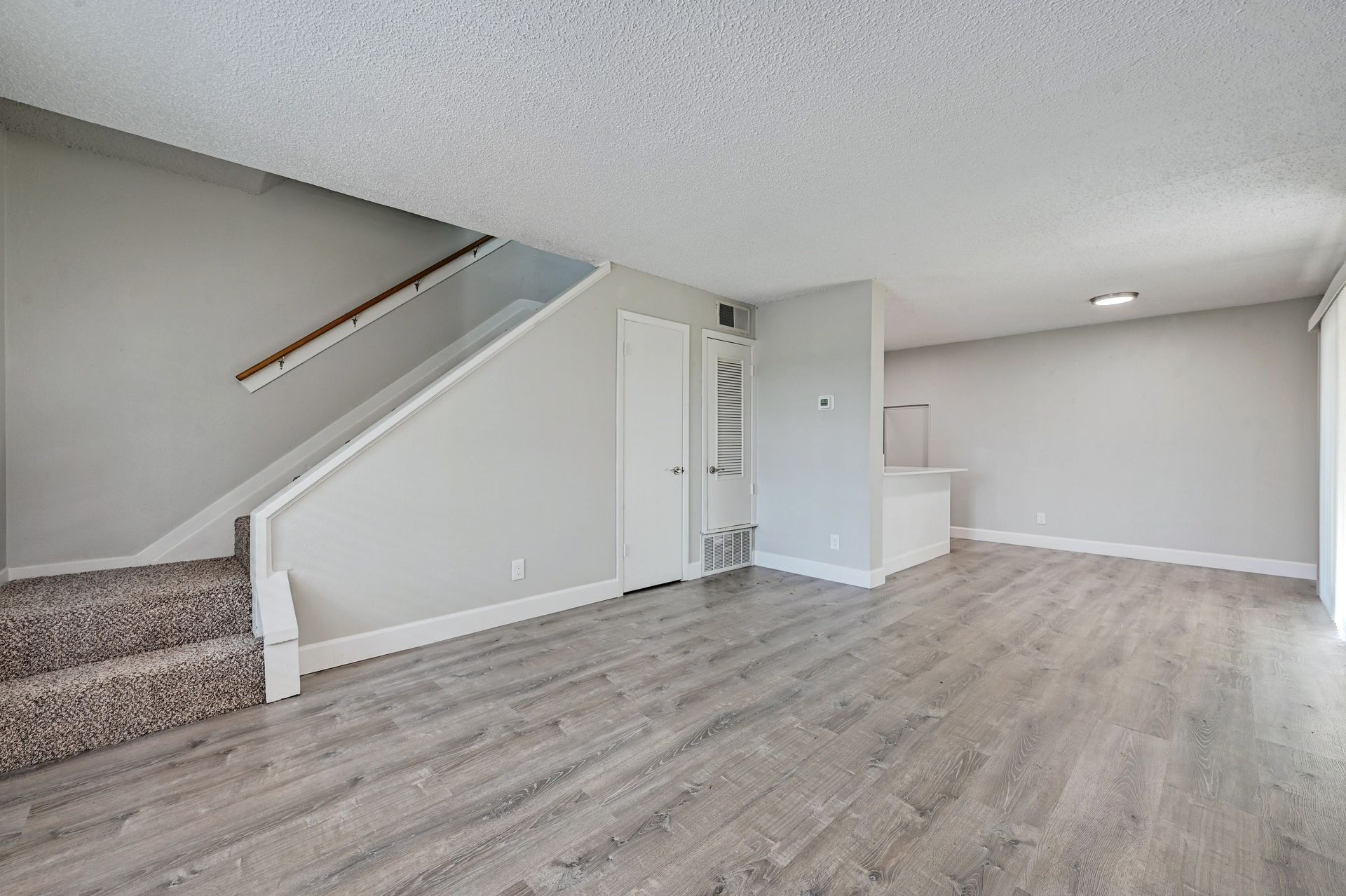 A living room with hardwood floors and stairs in a house.
