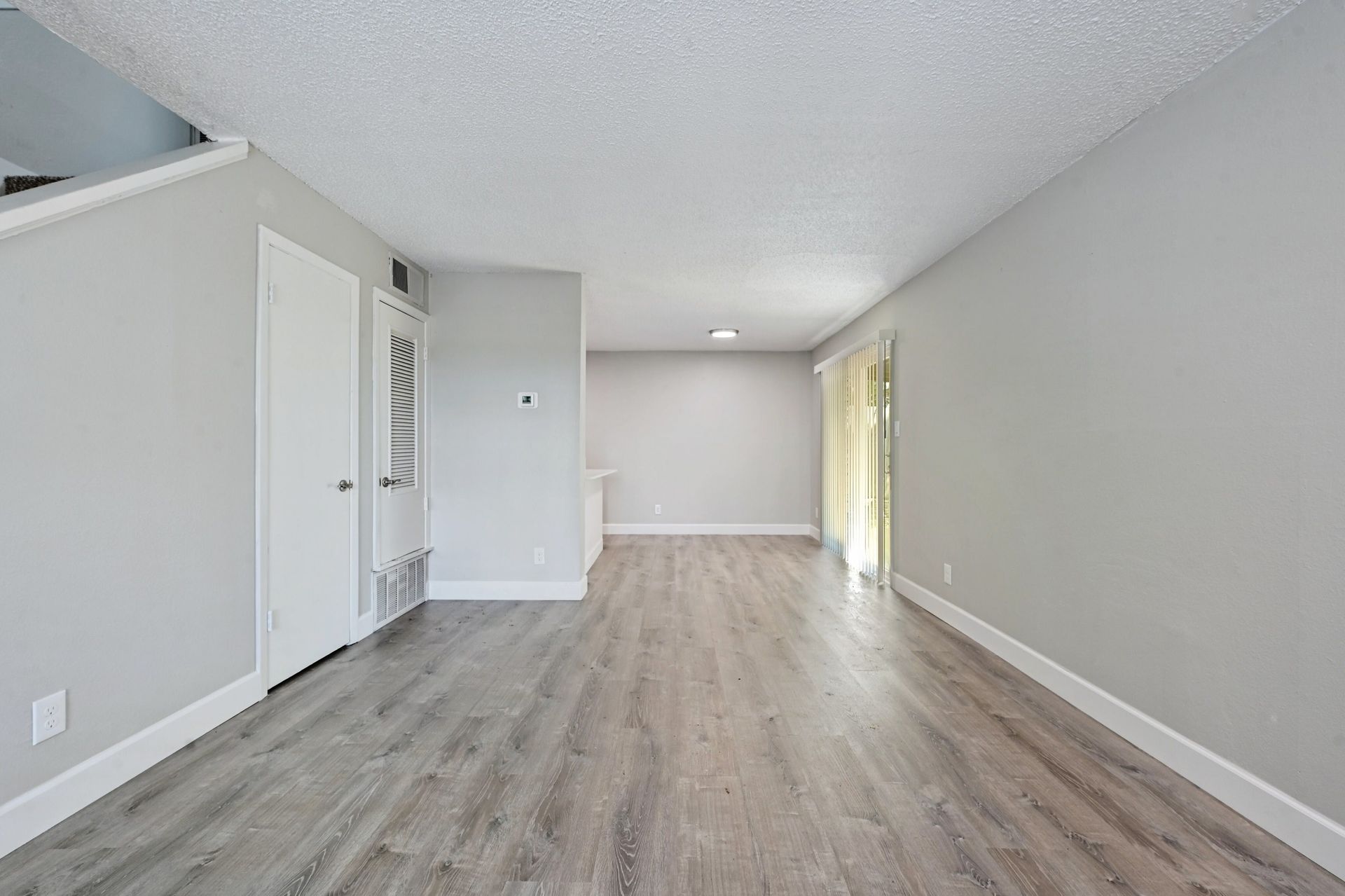 An empty living room with hardwood floors and gray walls.
