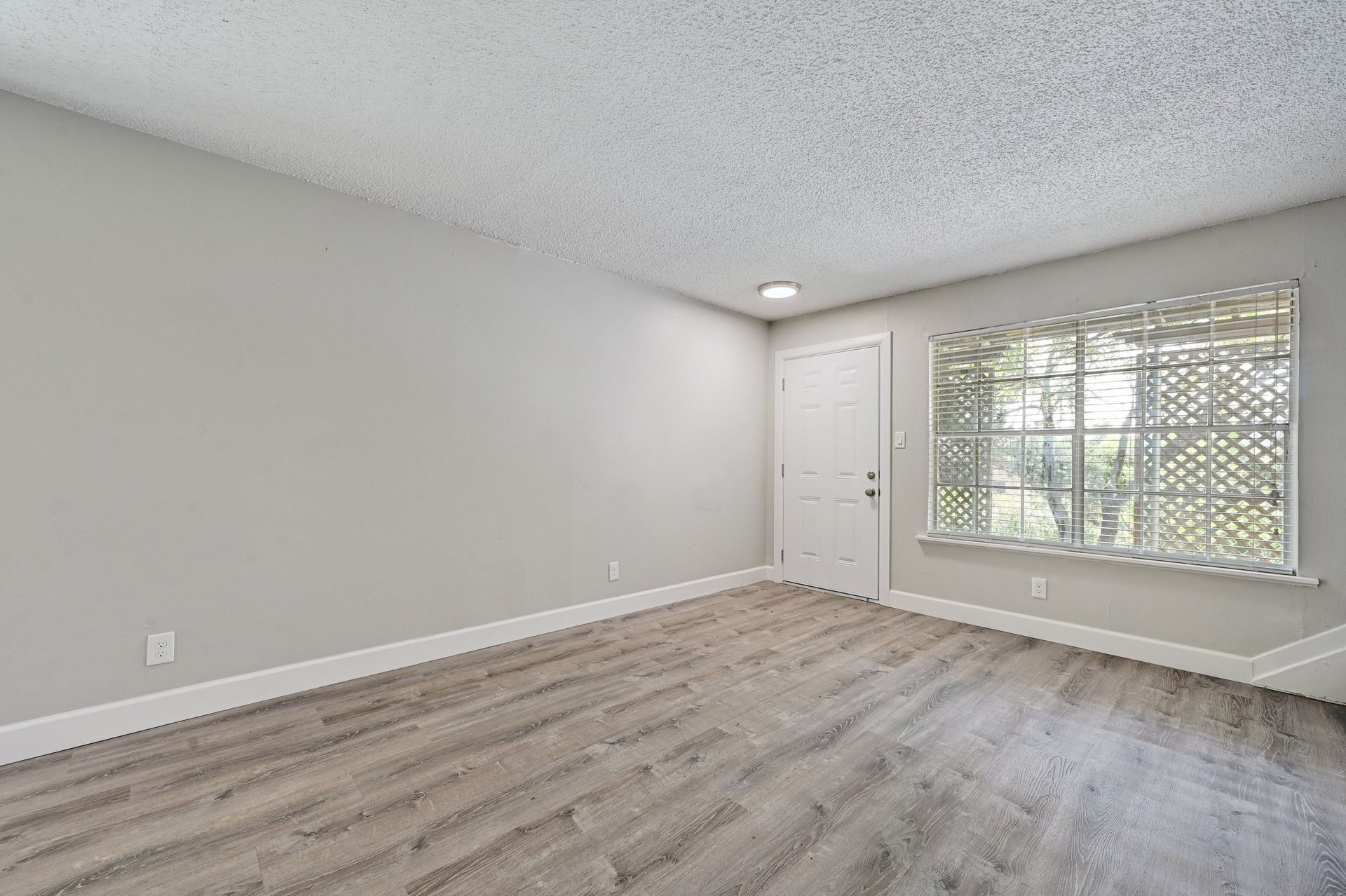 An empty living room with hardwood floors and a window.