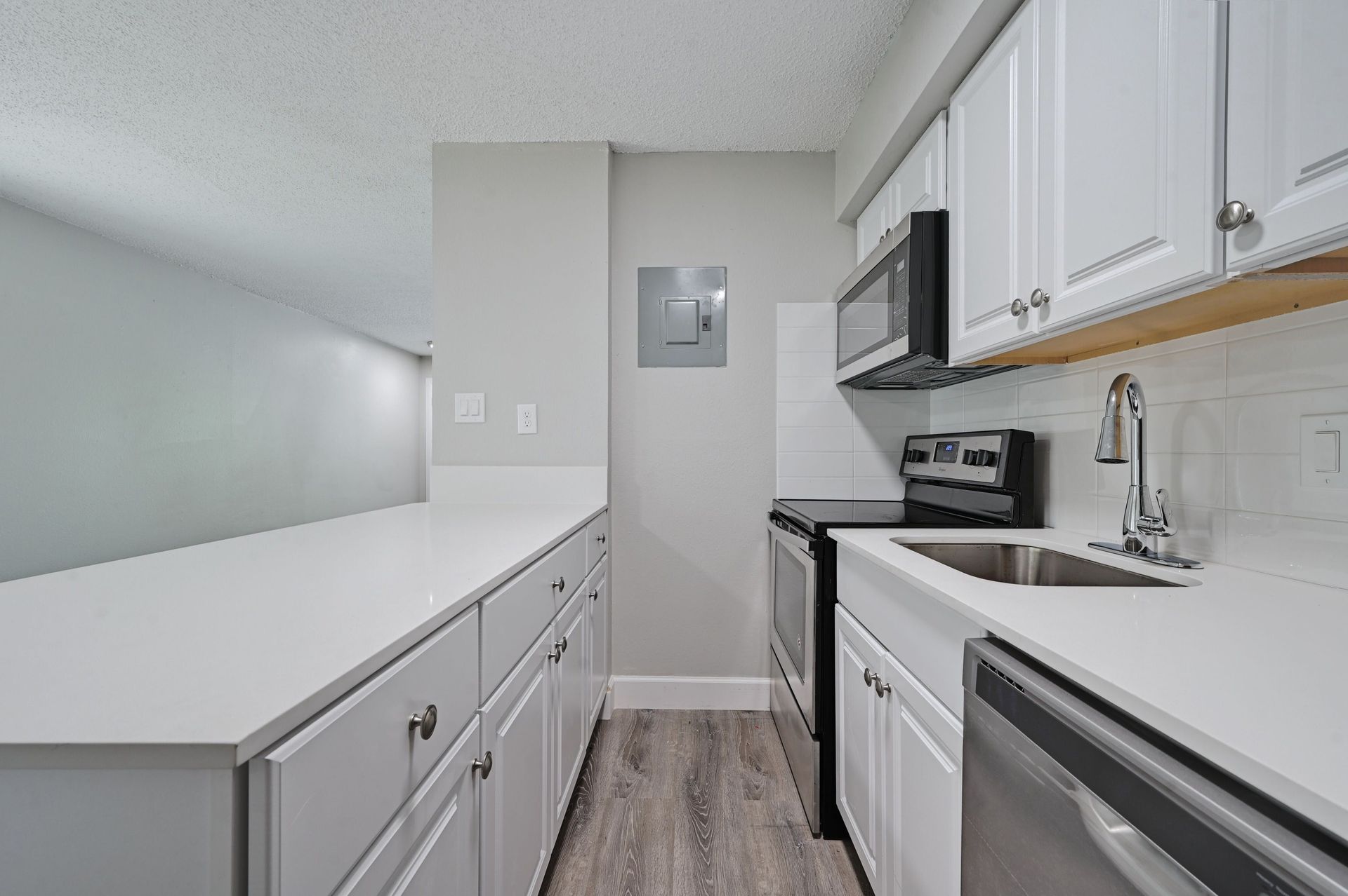 A kitchen with white cabinets , stainless steel appliances , and a sink.