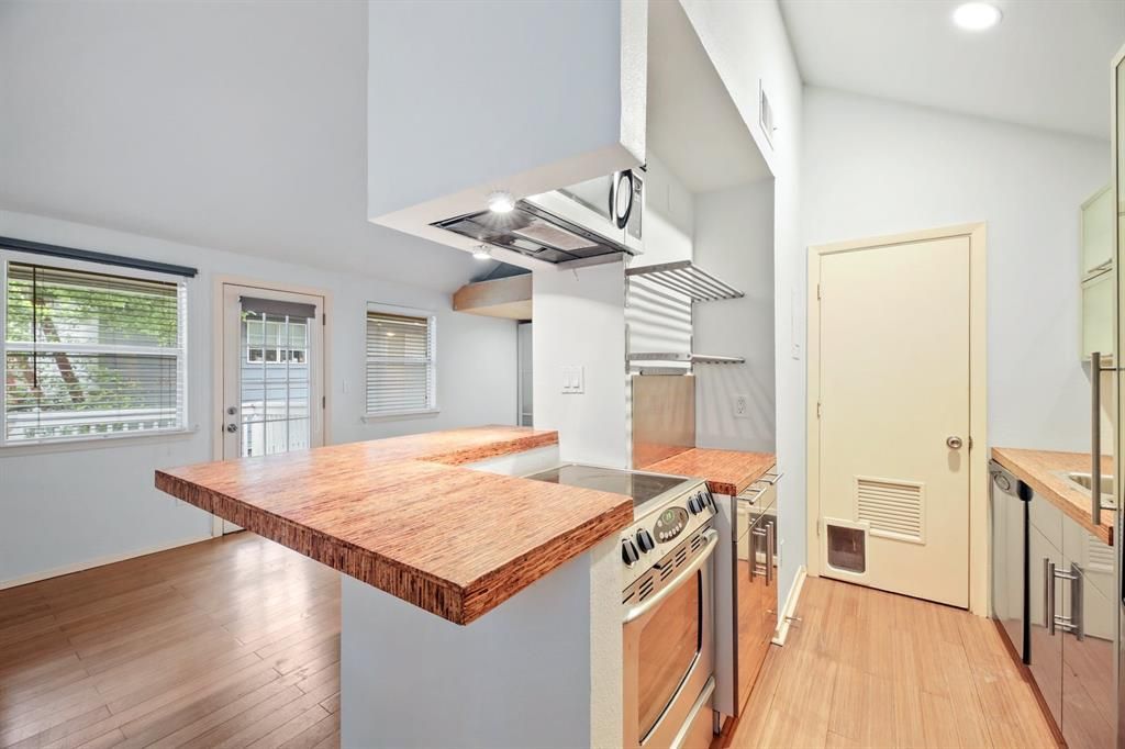An empty kitchen with stainless steel appliances and a cat door.
