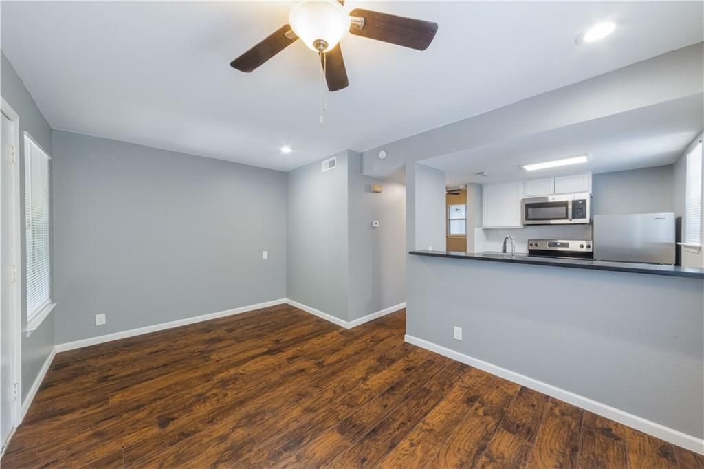 An empty living room with hardwood floors and a ceiling fan.