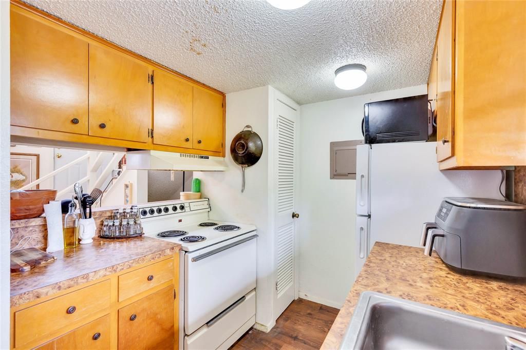 A kitchen with wooden cabinets , a stove , a sink , and a refrigerator.