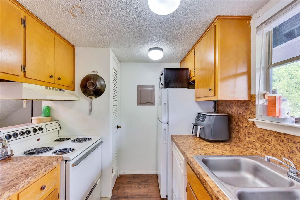 A kitchen with a stove , sink , refrigerator and microwave.