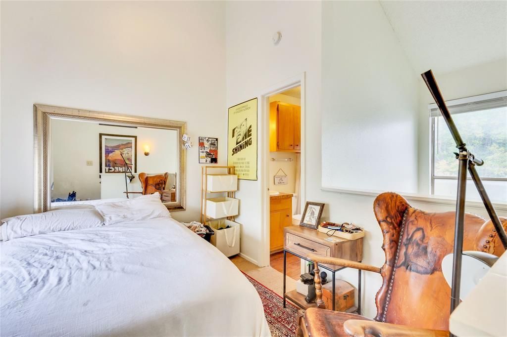A bedroom with a large bed and a chair