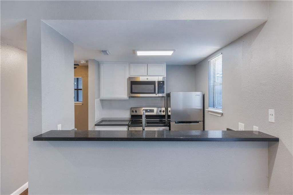 A kitchen with stainless steel appliances and a black counter top