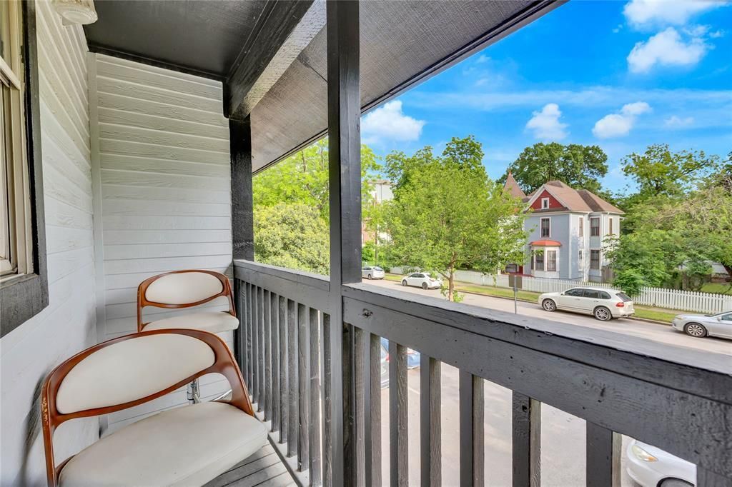A balcony with two chairs and a view of a street.