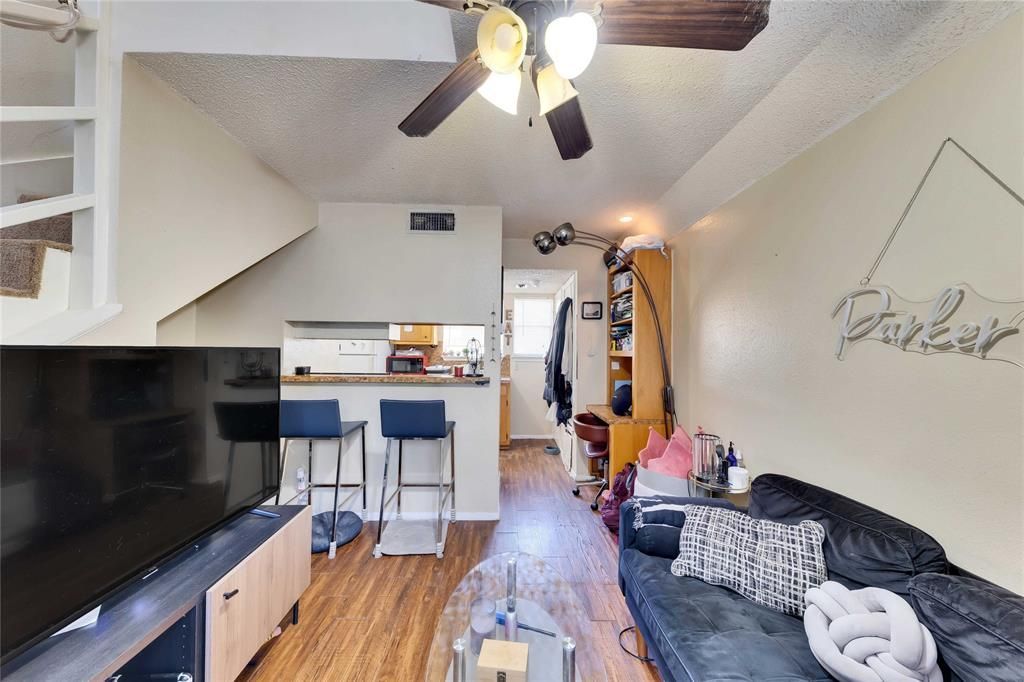 A living room with a ceiling fan and a flat screen tv