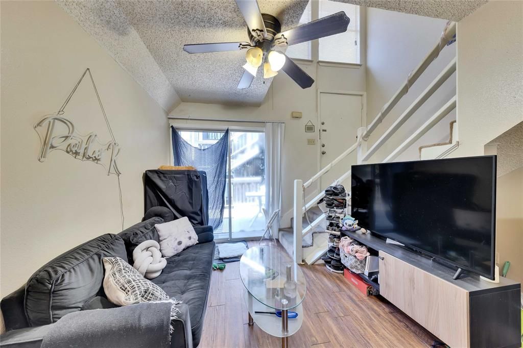 A living room with a ceiling fan and a flat screen tv