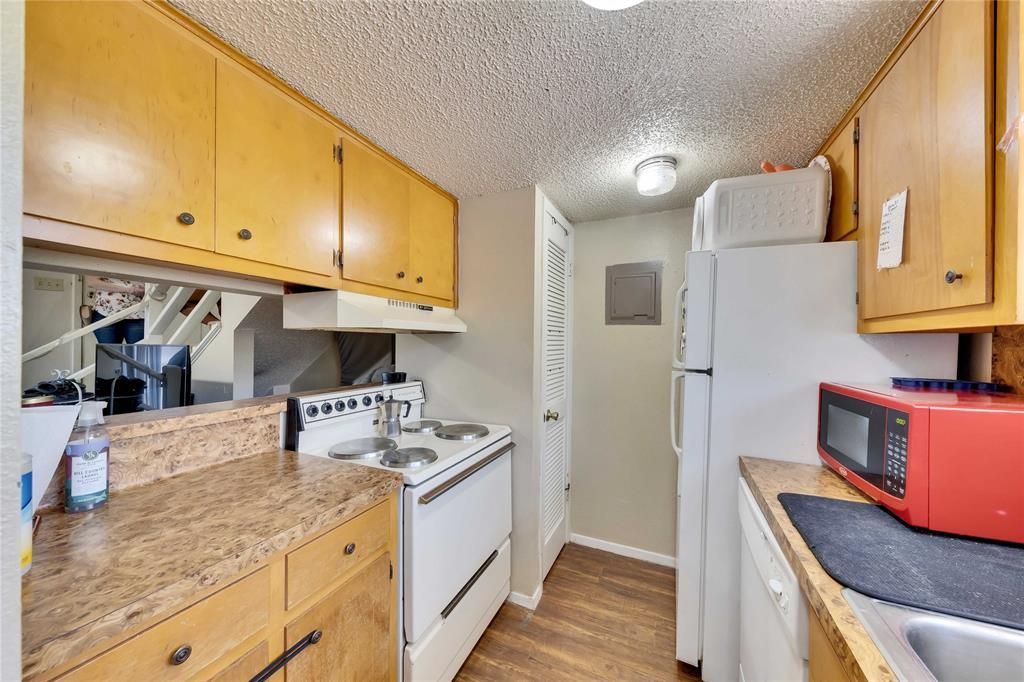 A kitchen with a stove , refrigerator , microwave and sink.
