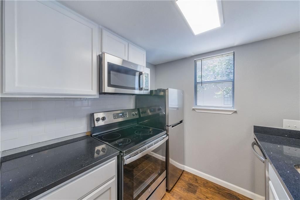 A kitchen with a stove , microwave , refrigerator and a window.