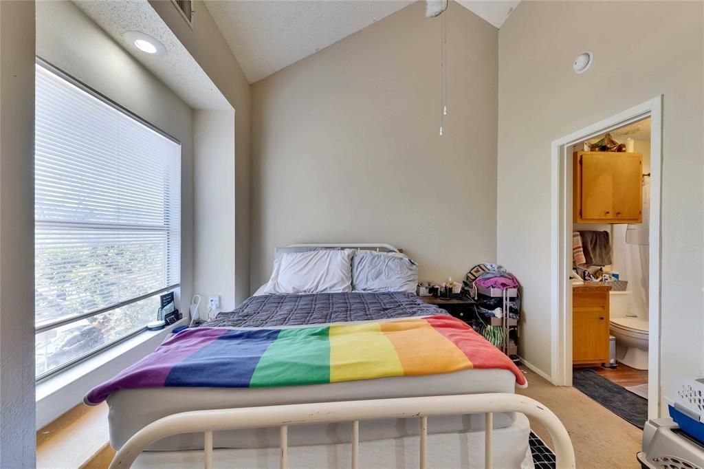 A bedroom with a bed with a rainbow blanket on it