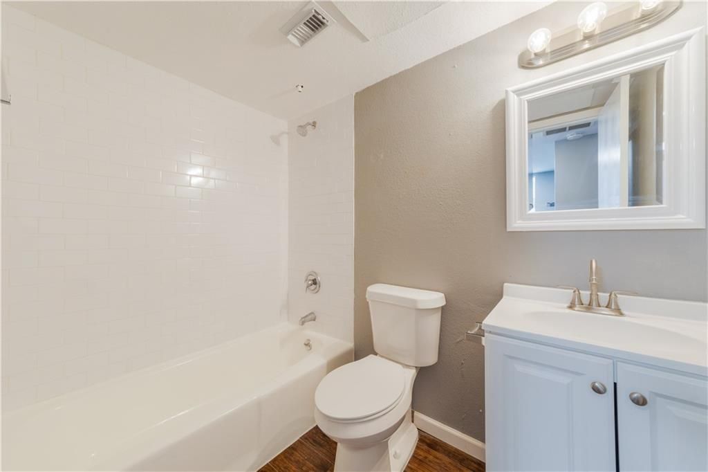 A bathroom with a toilet , sink , bathtub and mirror.