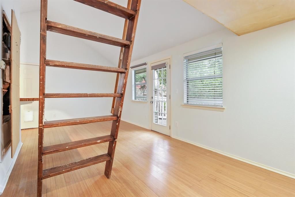 An empty room with a wooden ladder leading up to the second floor.