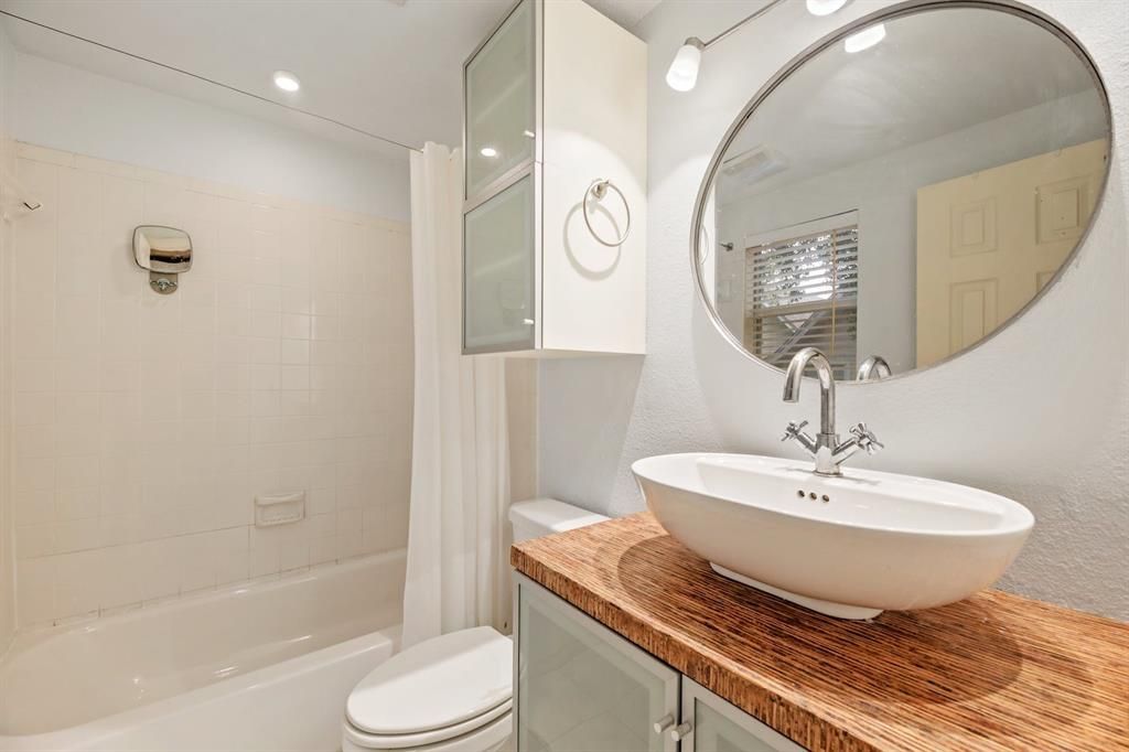 A bathroom with a sink , toilet , shower and mirror.