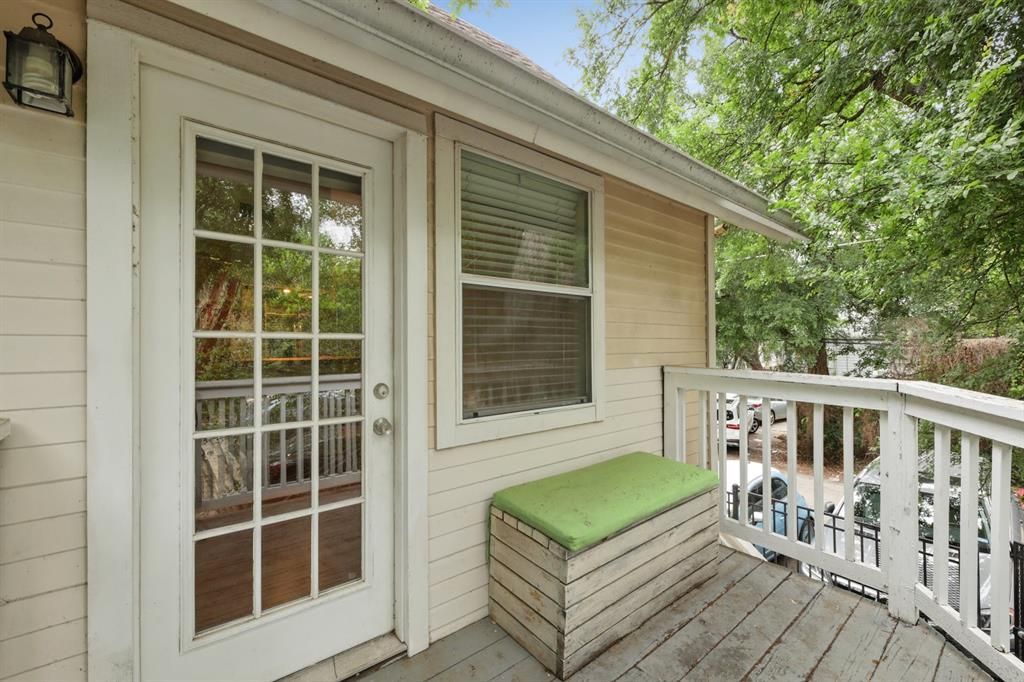 A small house with a porch with a bench and a sliding glass door.