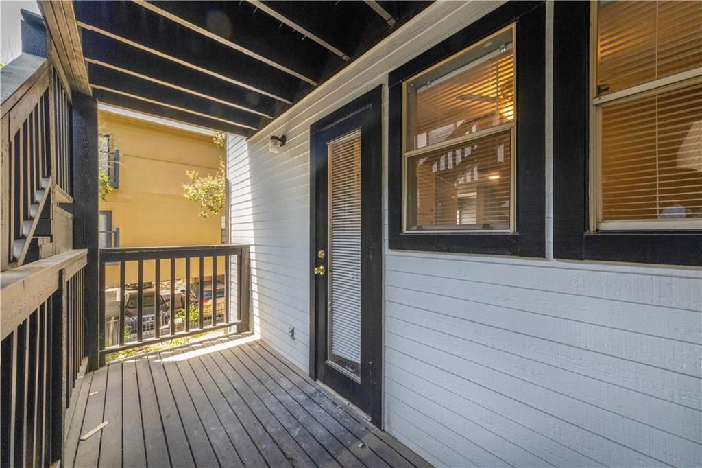 There is a porch with a black railing and a window.
