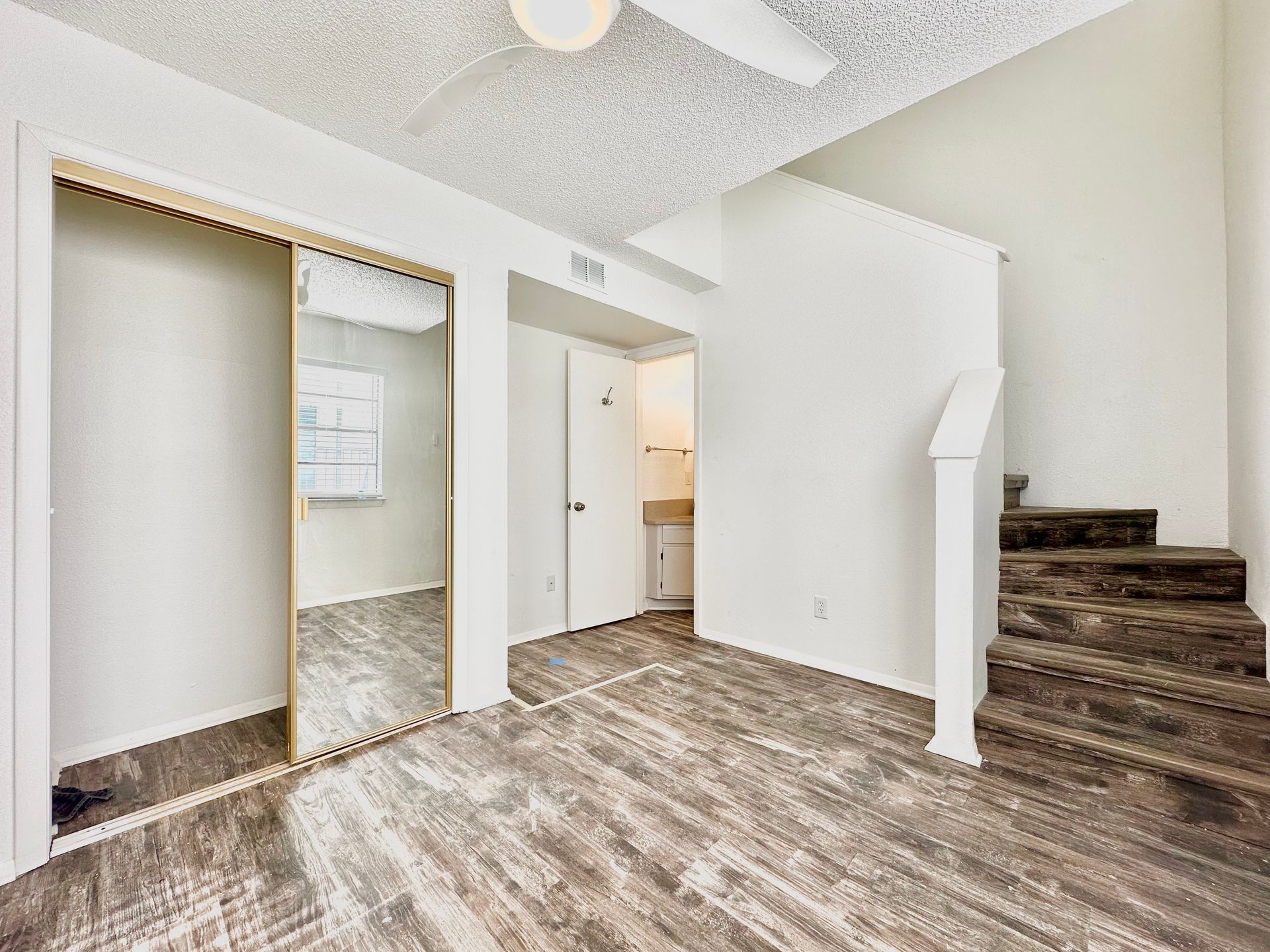 An empty living room with hardwood floors and stairs leading up to the second floor.