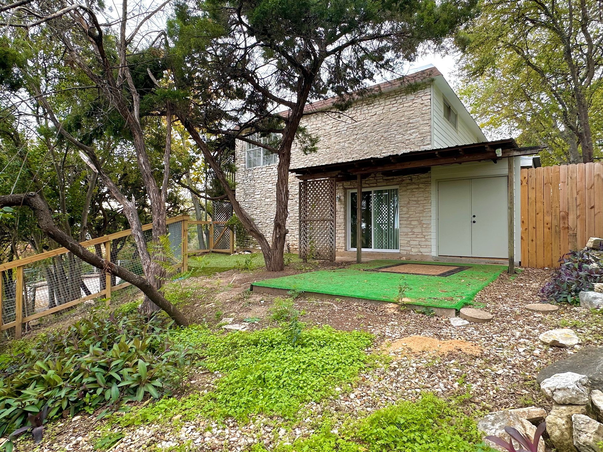 A house with a green lawn in front of it surrounded by trees.