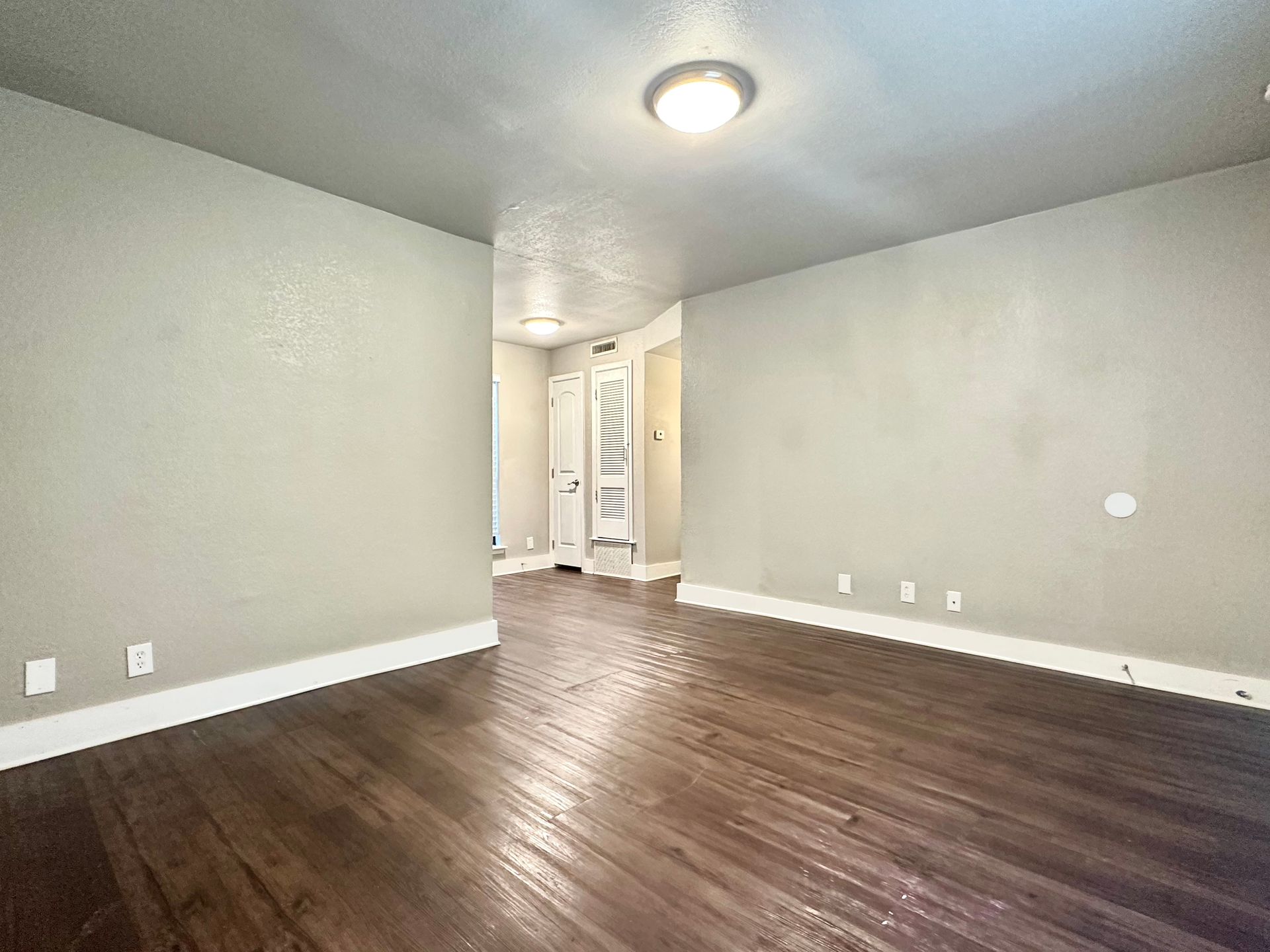 An empty room with hardwood floors and a light on the ceiling.