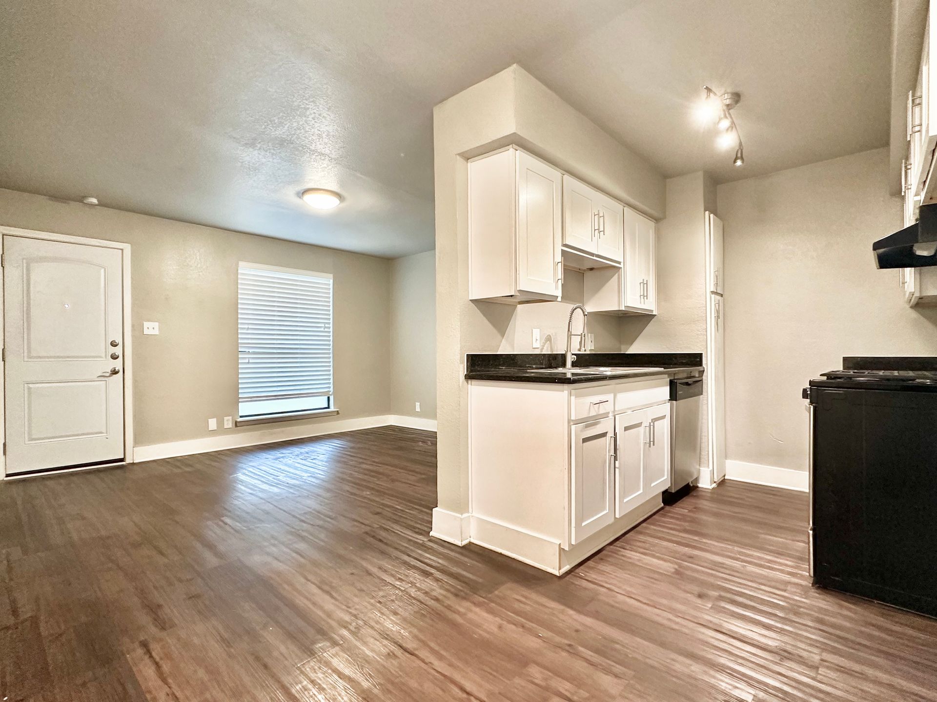 A kitchen with hardwood floors and white cabinets