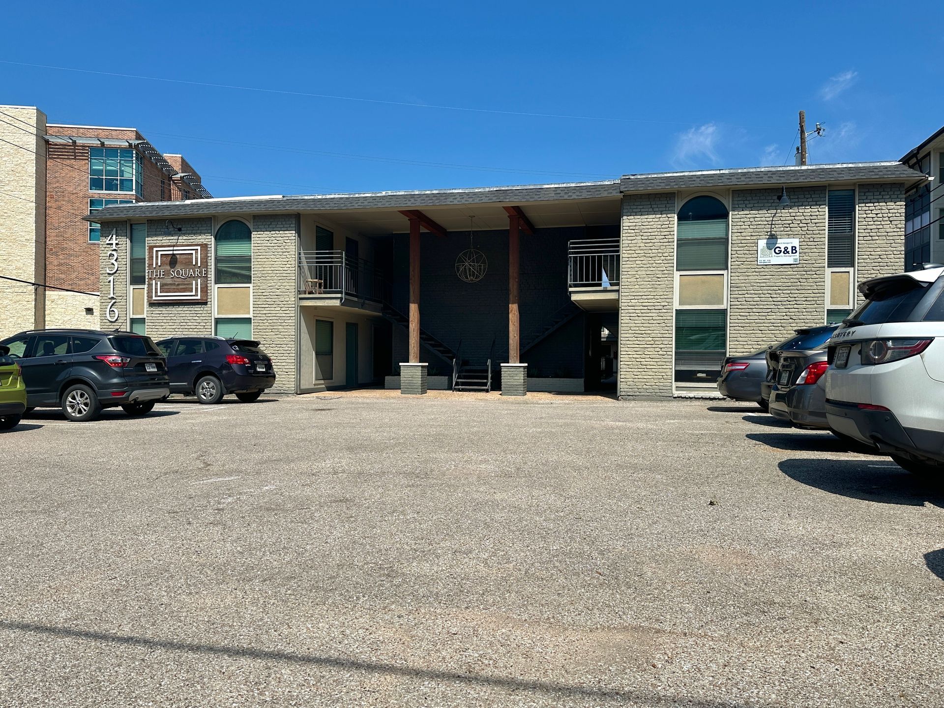 A row of cars are parked in front of a large building.