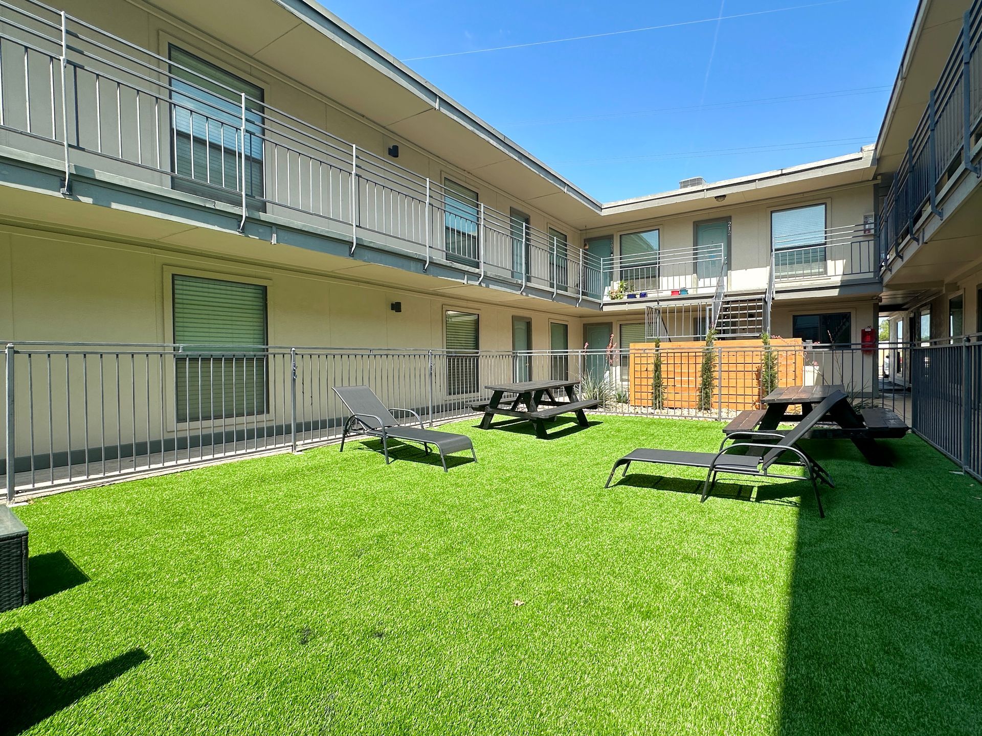 A courtyard with lawn chairs and picnic tables in front of a building.