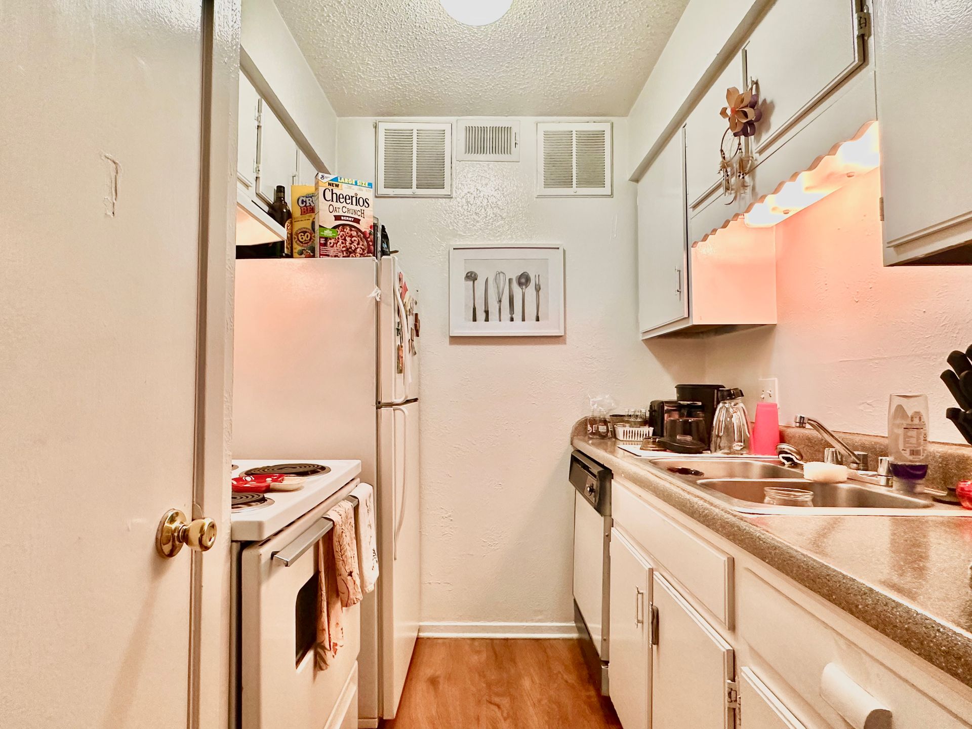 A kitchen with white cabinets and a picture of utensils on the wall