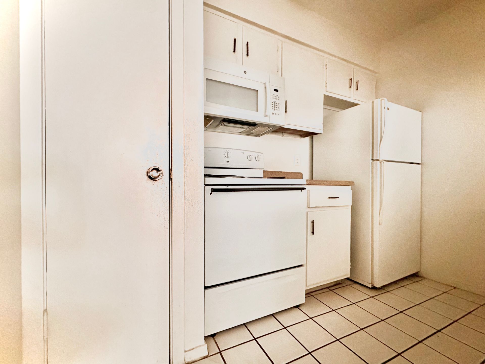 A kitchen with a stove , refrigerator , microwave and cabinets.